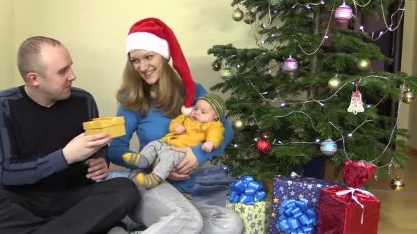 Cheerful family man and woman present gift for baby in Christmas — Stock Video