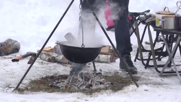 Tourist people cook in pot hanging over campfire fire in winter. 4K — Stock Video