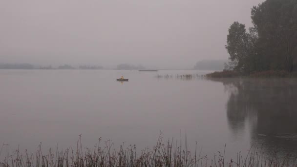 Fisher homem linha sentar em barco de madeira no lago coberto com densa névoa. 4K — Vídeo de Stock