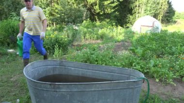 Köylü adam sulama olabilir ile su varil bahçede su çizin. 4k