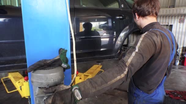 Monteur met hydraulische lift tot opheffing van de auto in de garage. — Stockvideo