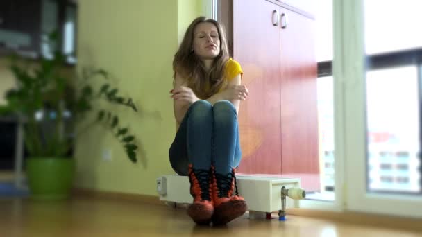 Jovem mulher colocar, boné sobre sentado no radiador frio — Vídeo de Stock