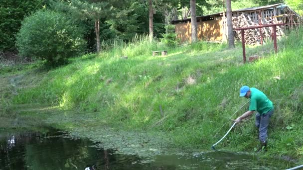 작업자는 여름에 시골 연못에서 낫으로 잔디를 grub. 4 k — 비디오