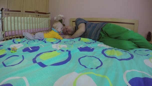 Уставший отец мужчина спит и милый новорожденный мальчик. 4K — стоковое видео