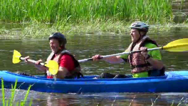Par av sportsmen rodd kanot genom floden mellan trädgrenar. Panorama — Stockvideo