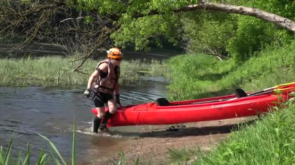 Woman carry canoe out of river water and other competition participants. — Stock Video