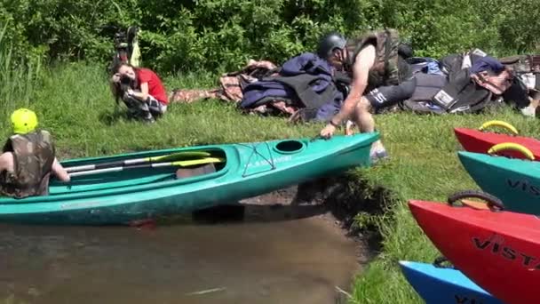 Pessoas ativas preparam canoa para viagem no lago e fotógrafo com câmera — Vídeo de Stock