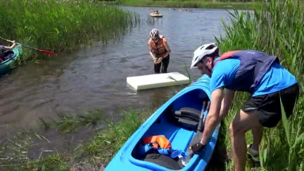 Ενεργοί άνθρωποι με κράνη που επιπλέουν σε κανό και αφρό στο νερό της λίμνης. — Αρχείο Βίντεο