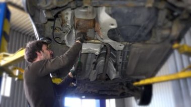 Bir arabanın altında bir tamirci ile otomatik tamir dükkanında köprüde egzoz