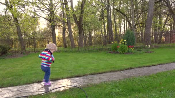 Barn flicka gå på Stig, våt efter regn i sommarträdgård. — Stockvideo