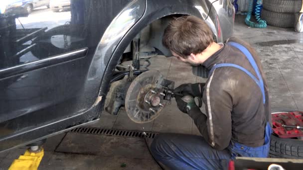 Careful worker guy repairing car brake system in garage. — Stock Video