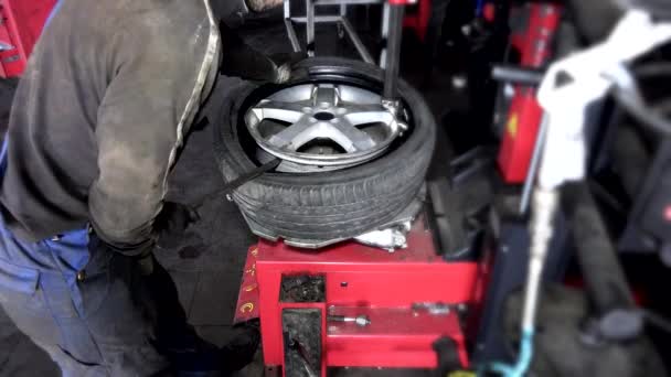 opravář práce s kolo pneumatiky na vyvažovači na opravárenské služby. 4K