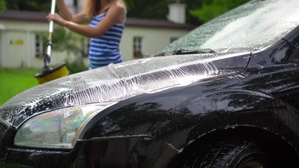 Unrecognizable woman washing car automobile hood with brush and shampoo — Vídeo de Stock