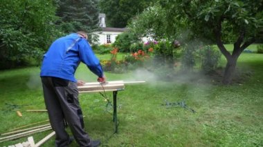 Handyman with protective mask and glasses polishing wood boards with grinder