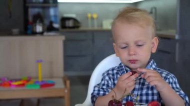 Baby boy eating cherries in kitchen. Cherries on a table. Gimbal movement