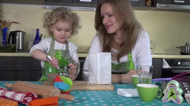 Fille mélanger mélange de farine et maman goûte dans la cuisine. Tir coulissant. 4K — Video