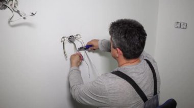 Kesici maşayla kablo kesen bir işçi. Elektrik kurulumu çalışıyor