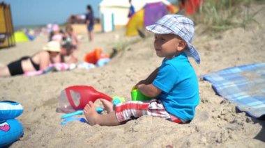 Küçük çocuk kumsalda kum ve oyuncaklarla oynuyor. Mutlu çocuk iyi eğlenceler.
