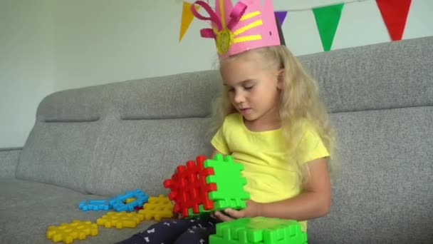 Księżniczka dziecko z koroną zbierając kolorowe części na kanapie. Ruch Gimbala — Wideo stockowe