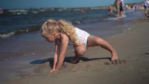 Vorschulmädchen graben Loch in Sand. Weibliches Kind im Badeanzug genießt Meereswellen — Stockvideo
