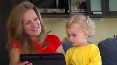 Anne ve bebek kanepede Skype tabletinden konuşuyorlar. 4K