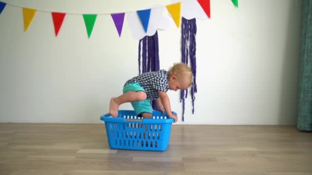 Een gelukkige zoon zit in een washok en speelt met een grote bal. Gimbal motie — Stockvideo