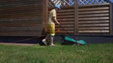 Evinin arka bahçesinde çim biçen bir adam. Gimbal hareketi