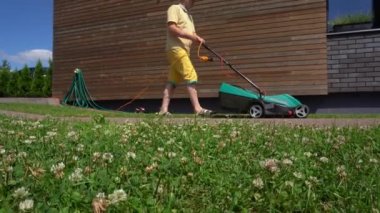 Çim biçme makineli bahçıvan arka bahçede çim biçiyor. Gimbal tava vuruşu