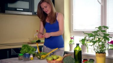 Mutlu hamile kadın, cam kasede sebze salatasıyla sarı kaşıkları karıştırıyor.