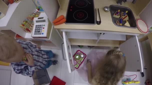 Soeur et frère jouent avec la cuisine de jouet dans le centre de jeu intérieur. Gimbal top shot — Video