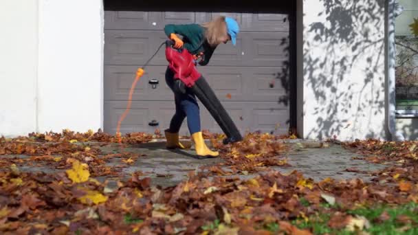 Loca mujer con soplador de hojas divertirse cerca del garaje — Vídeos de Stock