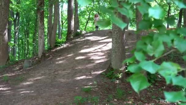 公園で急ピッチな丘を走ってピンクのドレスの幸せな女の子。ジンバル・モーション・ショット — ストック動画