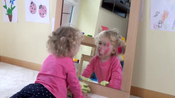 Mała radosna dziewczynka bawi się przed lustrem. Dzieciństwo. 4K — Wideo stockowe