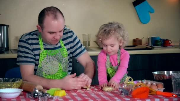 Отец учит маленькую дочь месить тесто для печенья на кухонном столе. 4K — стоковое видео