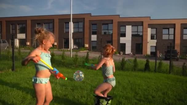 Chicas felices mejores amigos en trajes de baño jugando con pistolas de agua al aire libre — Vídeos de Stock