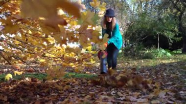 Ev bahçesindeki güzel lale ağacının altında yaprakları süpüren yetenekli bir kadın işçi.