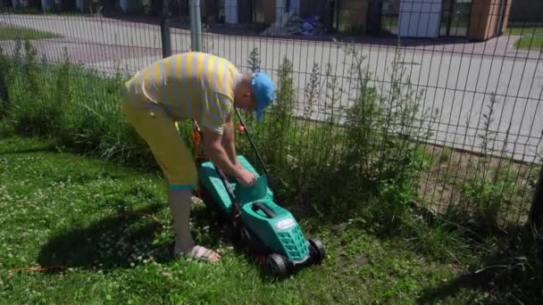 Gärtner Mann gießt gemähtes Gras über Zaun. Leichtsinniges Durcheinander. Gimbal-Bewegung — Stockvideo