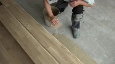 Spatulalı tamirci beton zemine ahşap yapıştırıcı sürmüş.