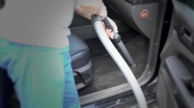 Arkaya bakan adam dışarıda elektrikli süpürgeyle araba süpürüyor. 4K