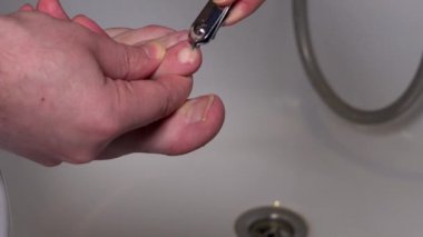 Adam tırnağını düzgün bir şekilde ucu ucuna kesmiş. Adam evde pedikür yapıyor. 4K