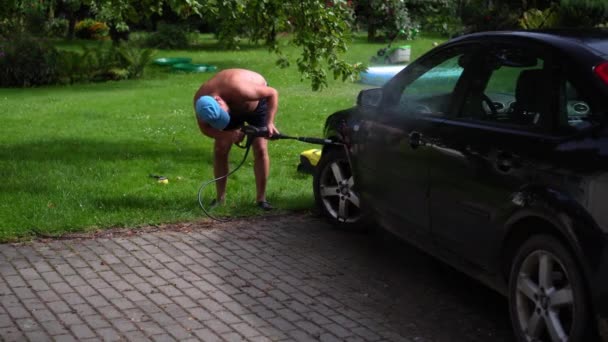 Férfi munkás meztelen nagy pocakkal mossa a saját kocsiját a kertben — Stock videók