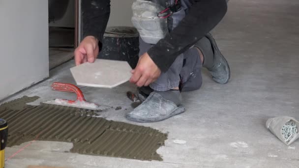 Trabajador enciende el láser y poner azulejos de piso hexágono — Vídeos de Stock