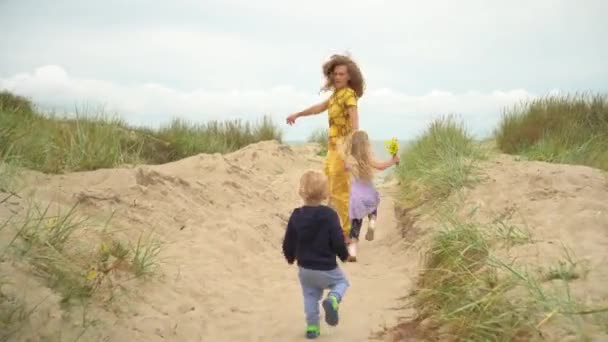 어머니와 딸 그리고 어린 아들 이 해변을 향해 나무로 된 길을 걷고 있는 모습 — 비디오