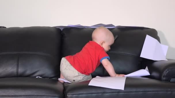 Kaukaski chłopiec zniszczyć dokumenty na kanapie w domu — Wideo stockowe