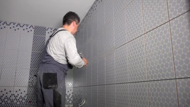 Мастер кладет фугу на настенные плитки в ванной комнате. Мужская черепица — стоковое видео