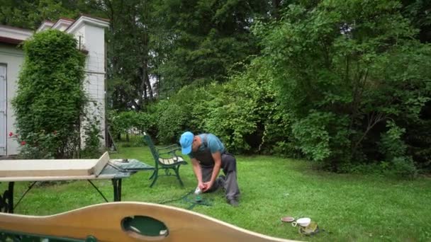 Hombre trabajador renovando marcos de muebles de exterior con amoladora — Vídeos de Stock