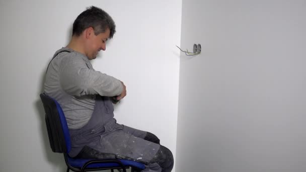 Чоловік готує дроти для з'єднання рамок розетки в отворах для стін з гіпсокартону — стокове відео