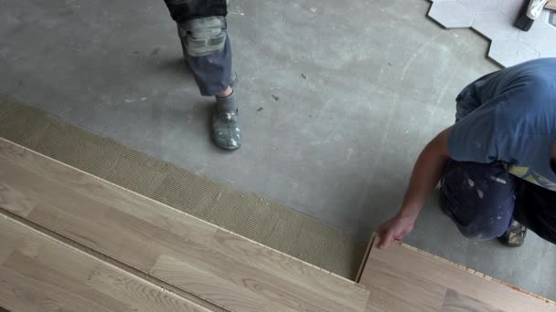 Építőipari munkások raknak tölgy parketta padlólapok új lakás — Stock videók