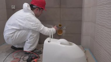 Usta zanaatkar banyoda tamirat yapıyor, tuvaleti asmaya hazırlanıyor. 4K