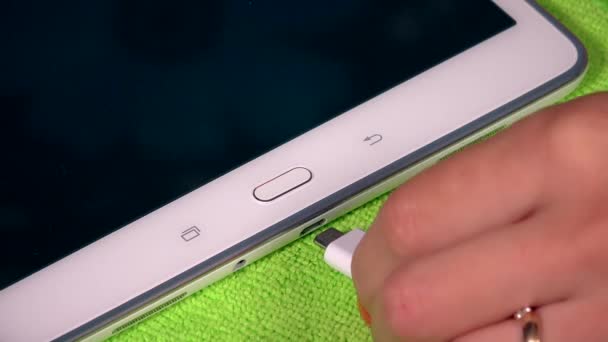 Vrouwelijke hand aansluiten op oplader mobiele telefoon en tablet op groen oppervlak. 4K — Stockvideo